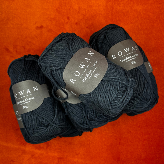 “Eight skeins of Rowan Handknit Cotton yarn in black, 100% cotton DK weight, neatly arranged in a yarn bundle.” top