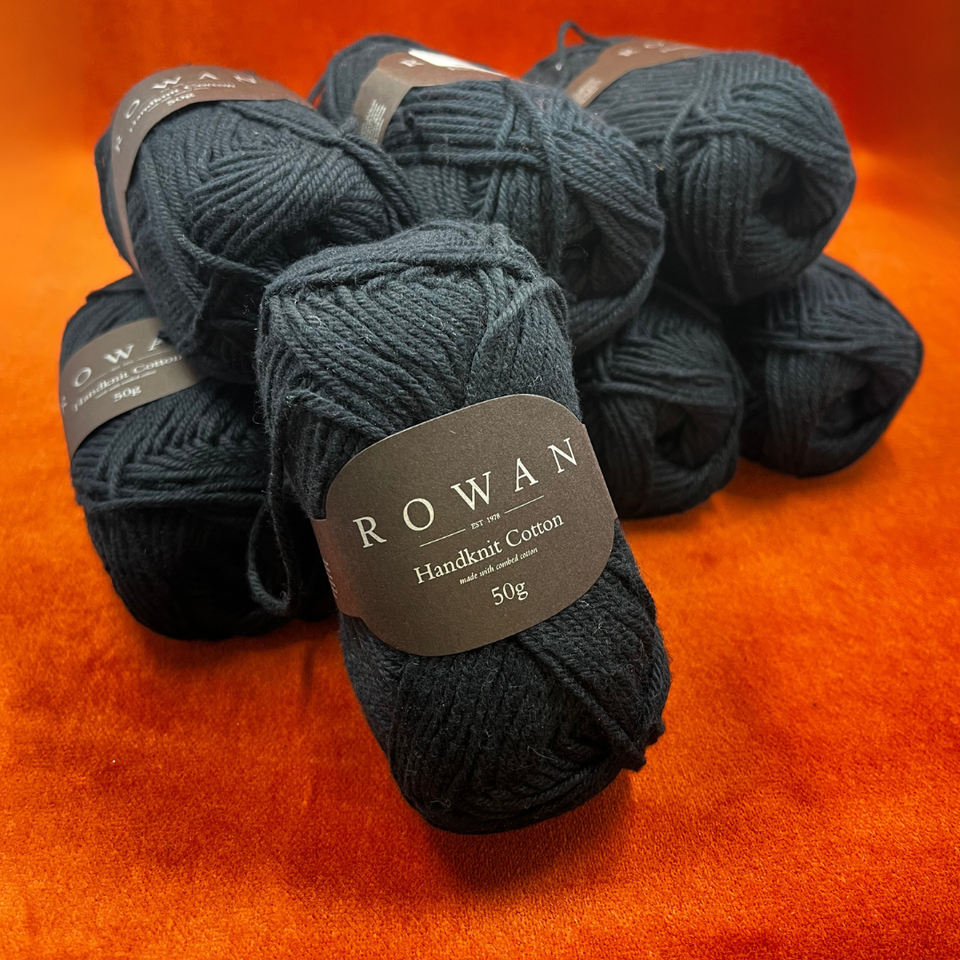 Eight skeins of Rowan Handknit Cotton yarn in black, 100% cotton DK weight, neatly arranged in a yarn bundle.