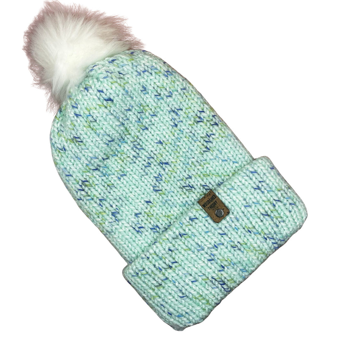 Teal blue chunky knit beanie with removable faux fur pom and faux cork tag, hand crafted by Woodshed Theory front