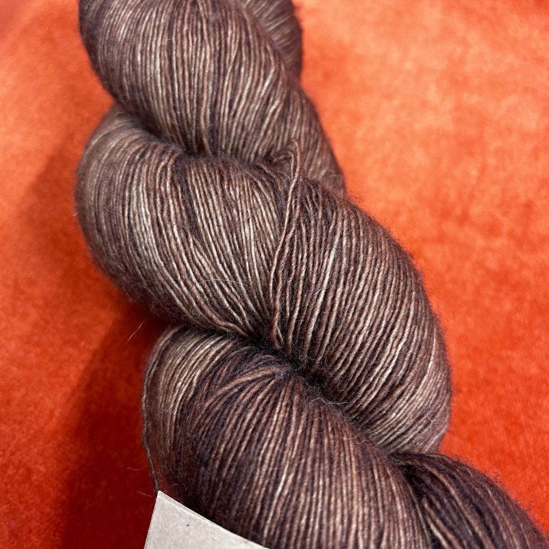 One skein of Madelinetosh Prairie yarn in Log Cabin Brown – a lace weight, single-ply superwash Merino yarn in rich earthy brown tones. close up color