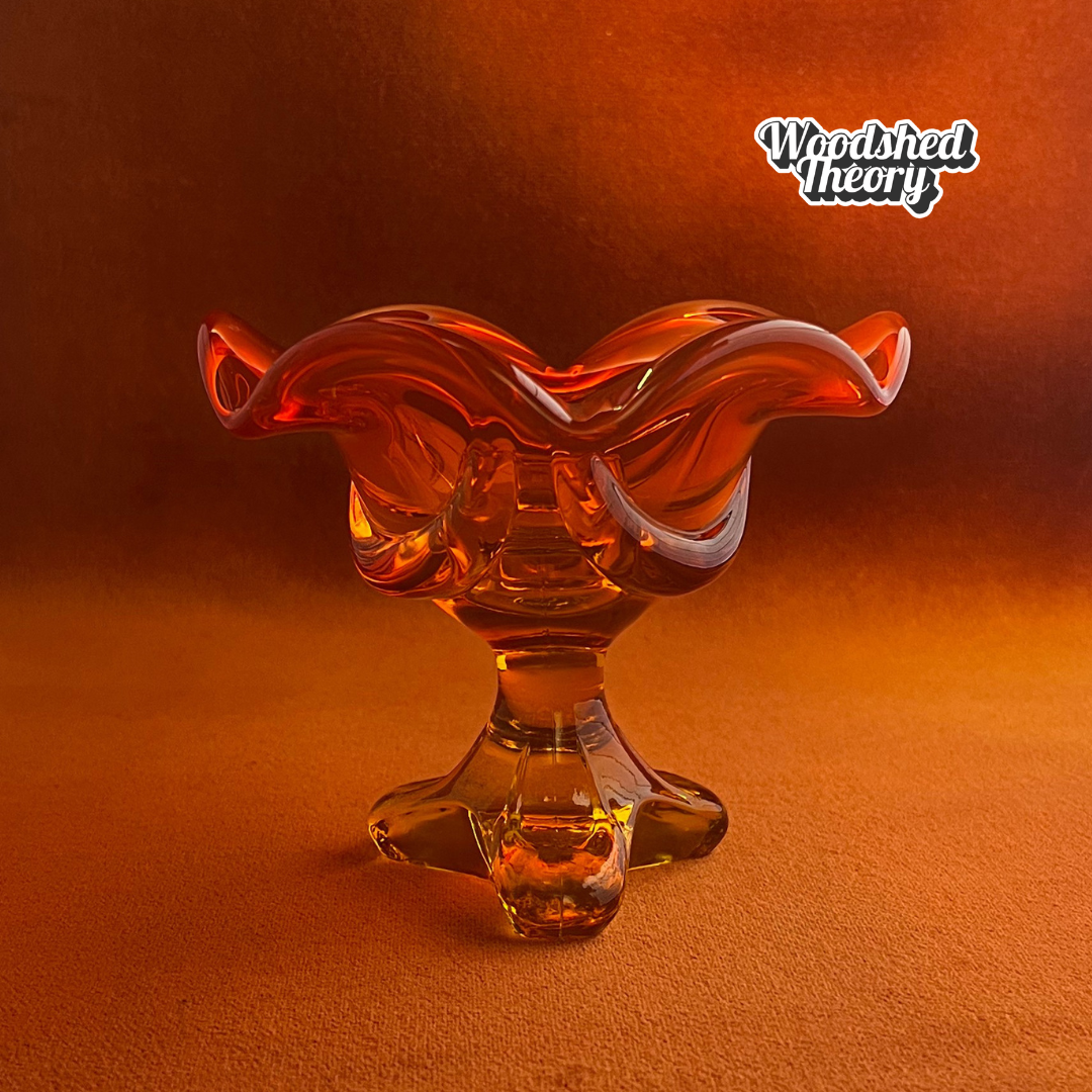 Viking Glass persimmon orange petal-shaped cadmium glass candle holder glowing under black light side view profile