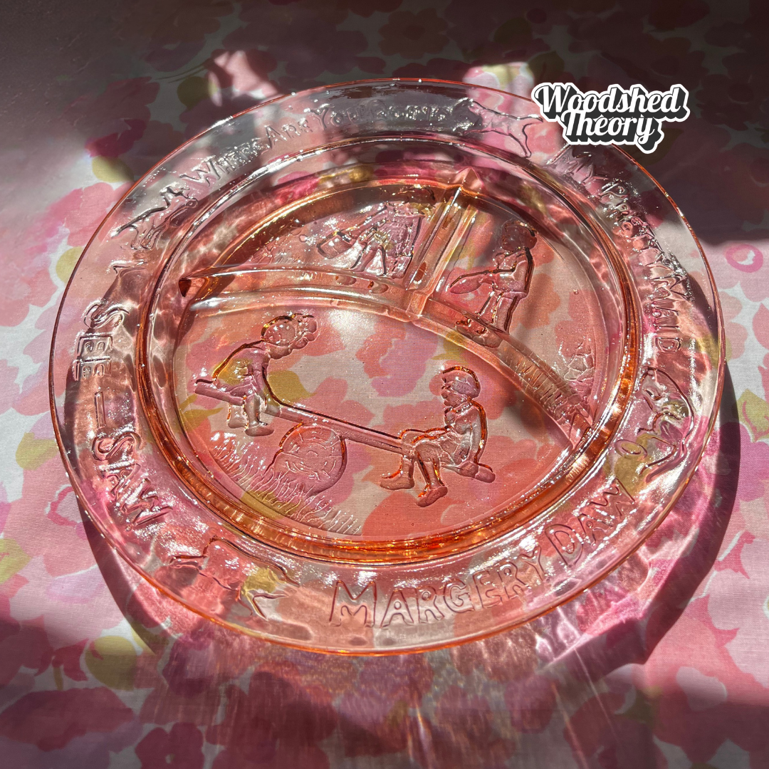 Vintage rose Depression glass children's plate with “Margery Daw” nursery rhyme design and three compartments. Circa 1930s–1940s. front glowing in the sun on pink
