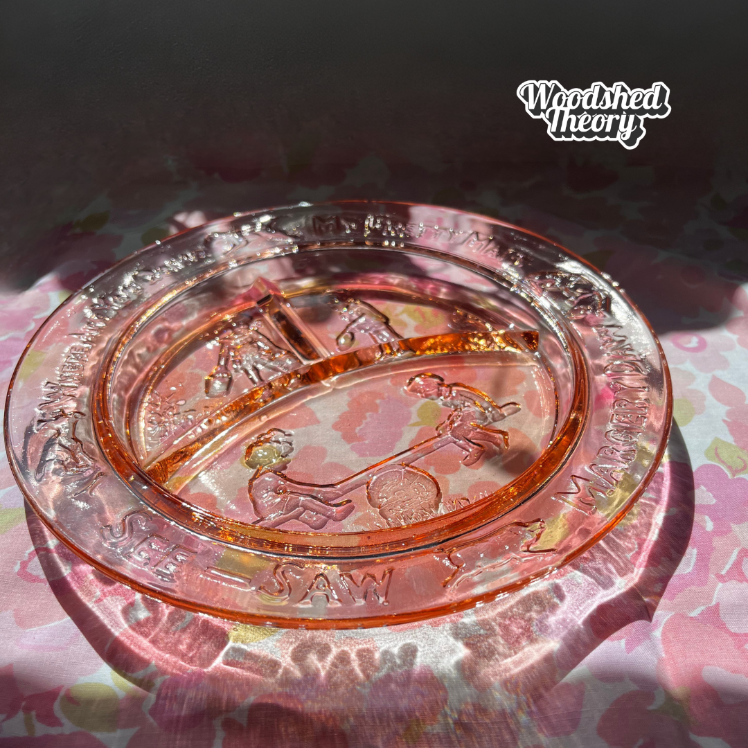Vintage rose Depression glass children's plate with “Margery Daw” nursery rhyme design and three compartments. Circa 1930s–1940s. other view lit in the sun