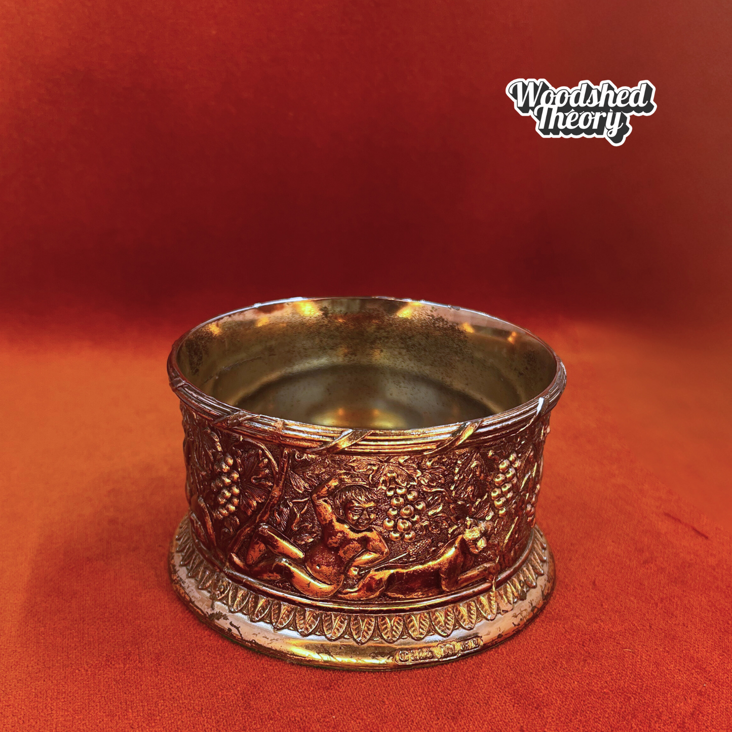 Fine English silver plate wine bottle coaster with cherub and grape design on a wood base. dog side
