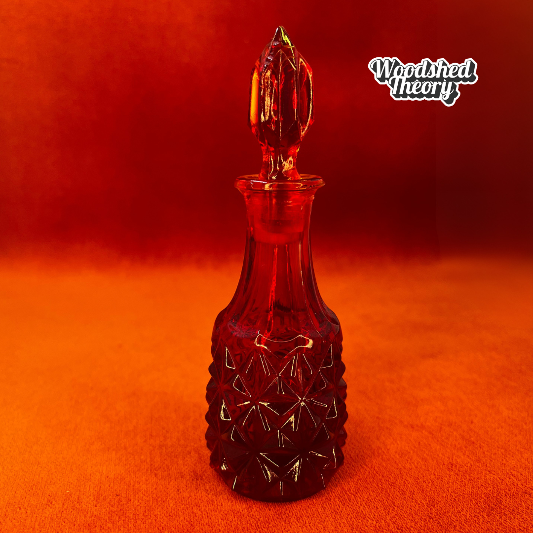 Amberina crystal vial with diamond facets and pointy stopper made in West Germany, glowing under black light front