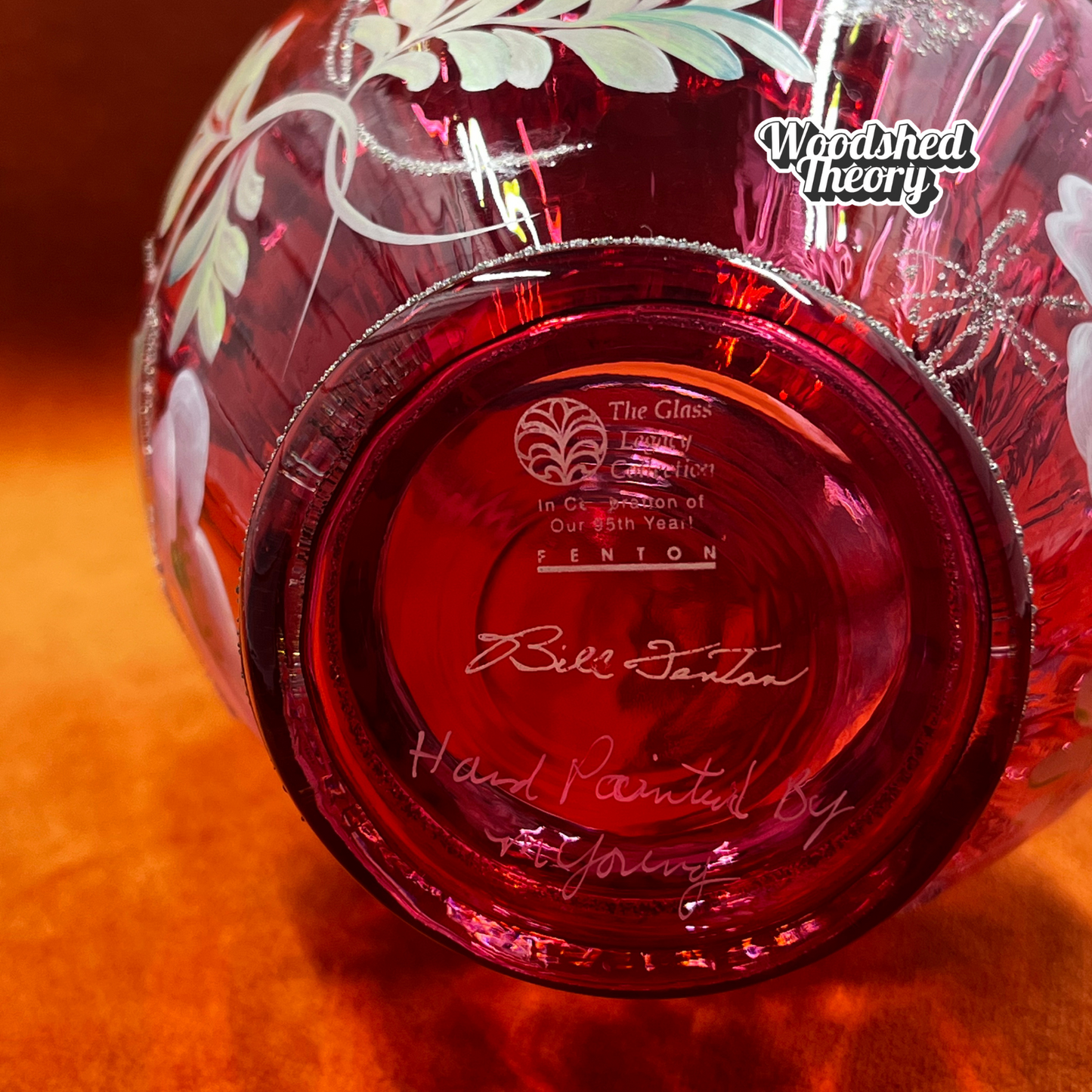 Fenton Art Glass cranberry basket with clear twisted handle, hand painted poppies, and gold glitter, signed by the artist. bottom 95th anniversary