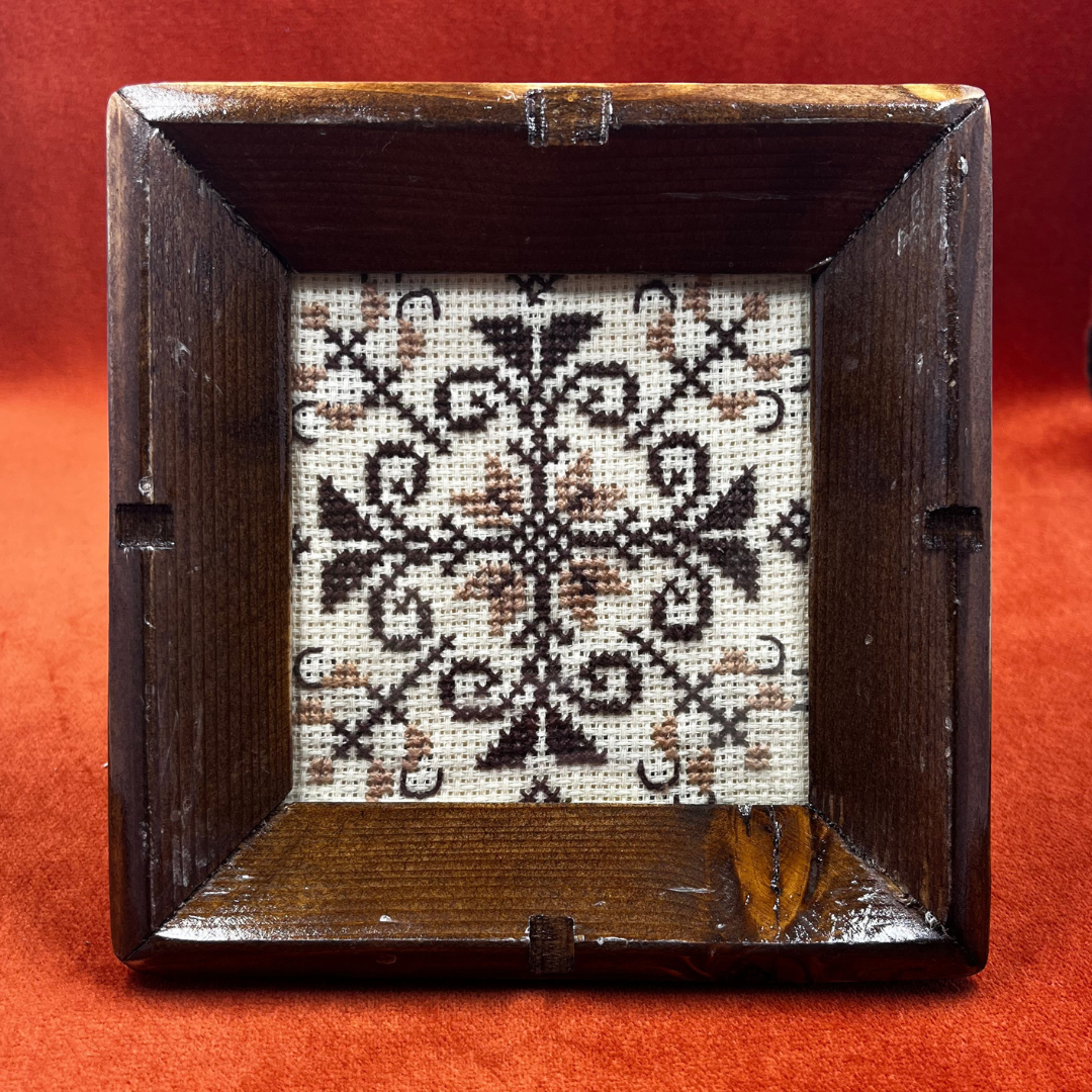 Set of 3 vintage wooden coasters with brown frames, glass covers, and retro cross stitch design in warm tones – perfect for drinks or wall art. close up front
