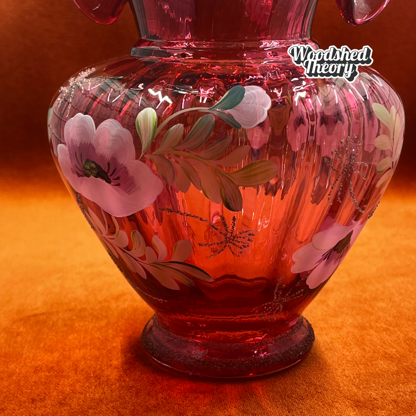 Fenton Art Glass cranberry basket with clear twisted handle, hand painted poppies, and gold glitter, signed by the artist. close up base