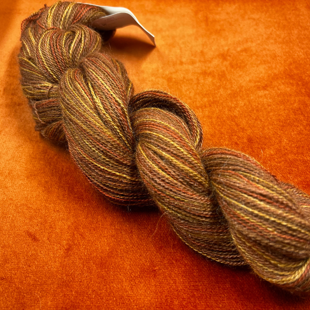 One hank of Knit Picks Shimmer lace weight yarn in a warm Spice color, made of baby alpaca and silk. close up