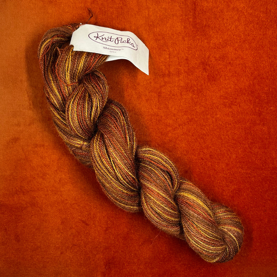 One hank of Knit Picks Shimmer lace weight yarn in a warm Spice color, made of baby alpaca and silk. top down
