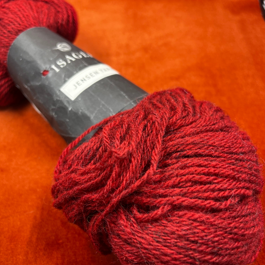 A single hank of Isager Jensen yarn in deep red (32s), 100% wool, neatly twisted and ready for knitting. close up.