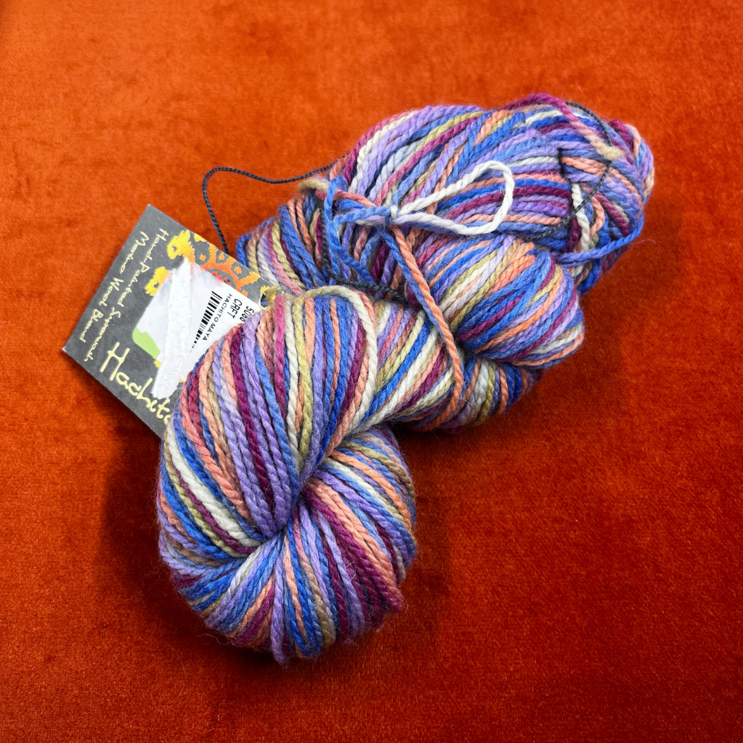 One hank of Mirasol Hachito fingering weight yarn in Maya, a superwash merino and nylon blend in rich, variegated tones. top down