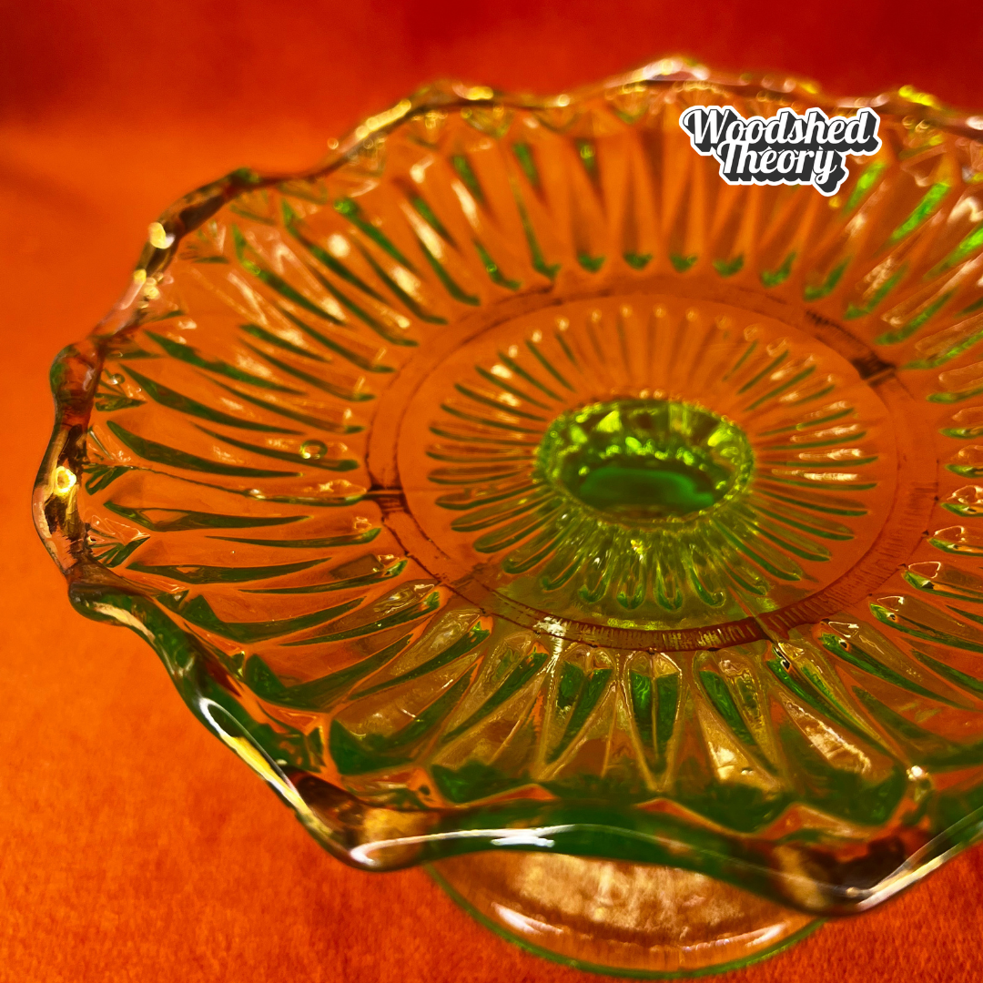 Vintage uranium glass candy or ring dish with ruffled edge and faded gold accents, collectible vaseline glass glowing green under black light. close up natural light detail