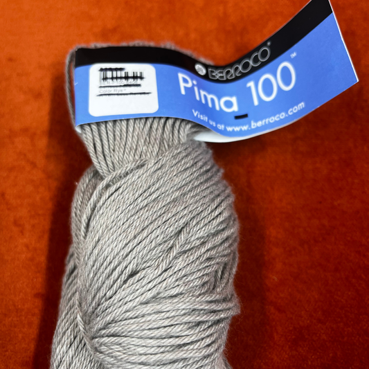 One hank of Berroco Pima 100 yarn in color Rye (8408), worsted weight matte beige cotton yarn. close up top