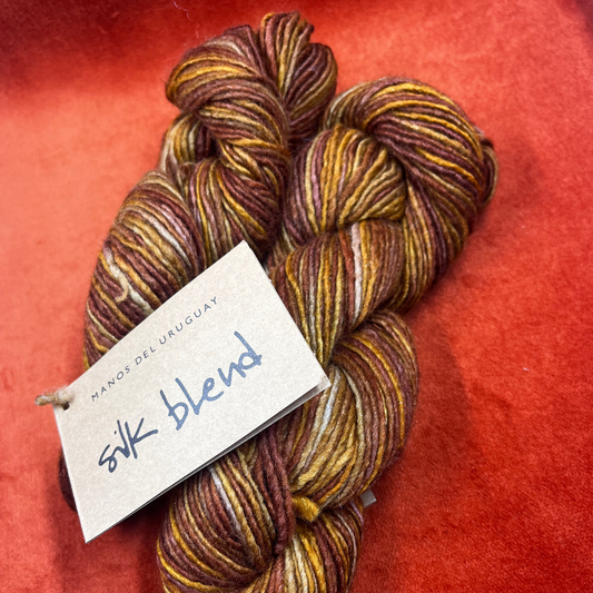 Two hanks of MANOS del URUGUAY Silk Blend yarn in the color Prairie, a hand-dyed blend of tussah silk and merino wool. close up bright light