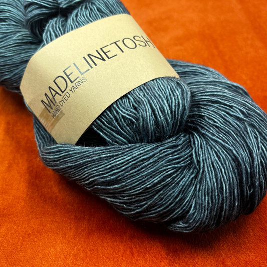 One skein of Madelinetosh Prairie yarn in Fog – a lace weight, single-ply merino wool yarn in deep teal tones. close up