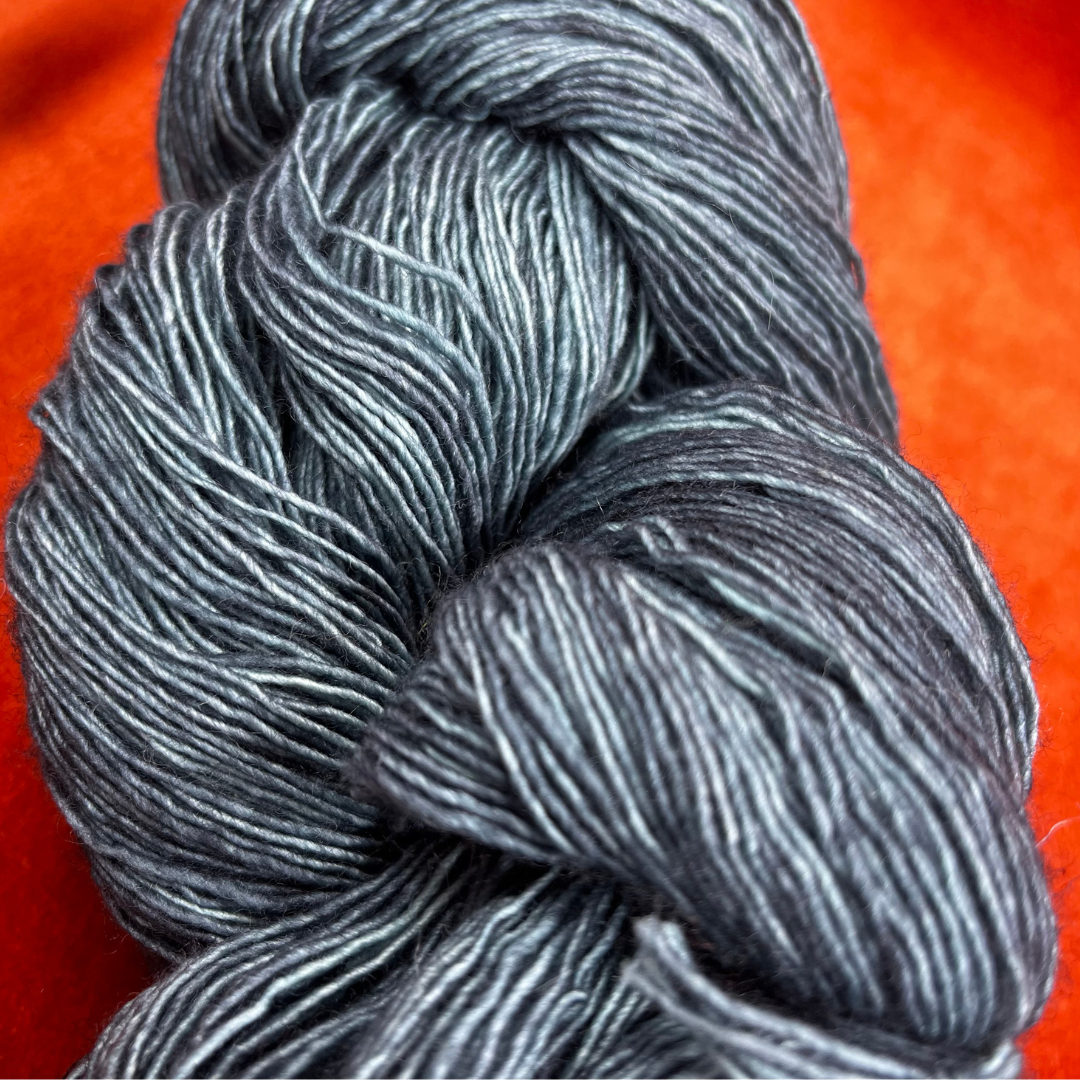 One skein of Madelinetosh Prairie yarn in Fog – a lace weight, single-ply merino wool yarn in deep teal tones. close up color