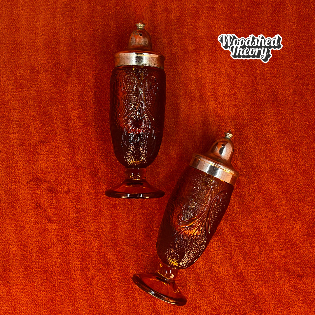 Pair of vintage amber pressed glass salt and pepper shakers with silver metal tops, green patina visible inside lids.Tiara Indiana Glass