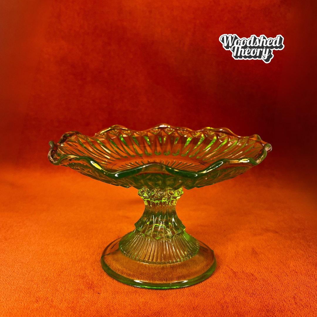Vintage uranium glass candy or ring dish with ruffled edge and faded gold accents, collectible vaseline glass glowing green under black light. natural light