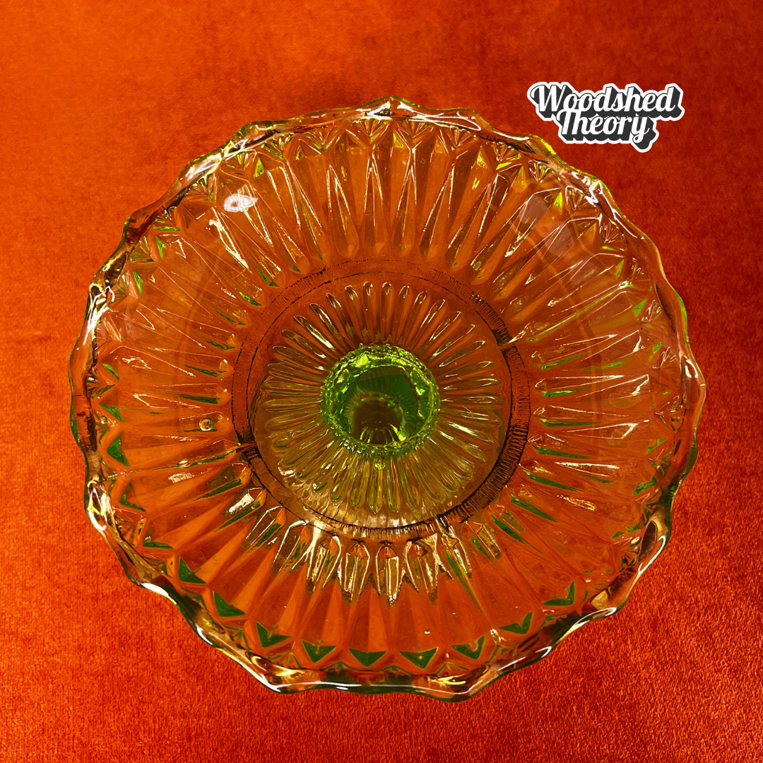 Vintage uranium glass candy or ring dish with ruffled edge and faded gold accents, collectible vaseline glass glowing green under black light. natural light top