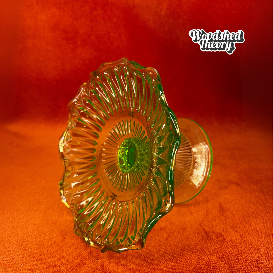 Vintage uranium glass candy or ring dish with ruffled edge and faded gold accents, collectible vaseline glass glowing green under black light. natural light side