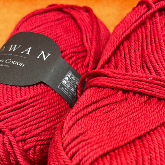 Two skeins of Rowan Handknit Cotton yarn in Rosso 215, a rich red color, displayed on a neutral background. Each ball is slightly unwound and may have minor label wear, reflecting its vintage condition. close up 