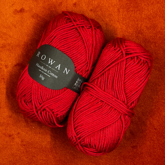 Two skeins of Rowan Handknit Cotton yarn in Rosso 215, a rich red color, displayed on a neutral background. Each ball is slightly unwound and may have minor label wear, reflecting its vintage condition.