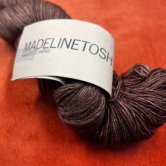One skein of Madelinetosh Prairie yarn in Log Cabin Brown – a lace weight, single-ply superwash Merino yarn in rich earthy brown tones. close up label