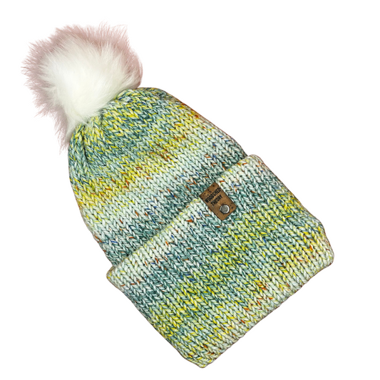 Green, blue, and yellow acrylic knit beanie with removable faux fur pom and faux cork tag, hand crafted by Woodshed Theory garden stroll 