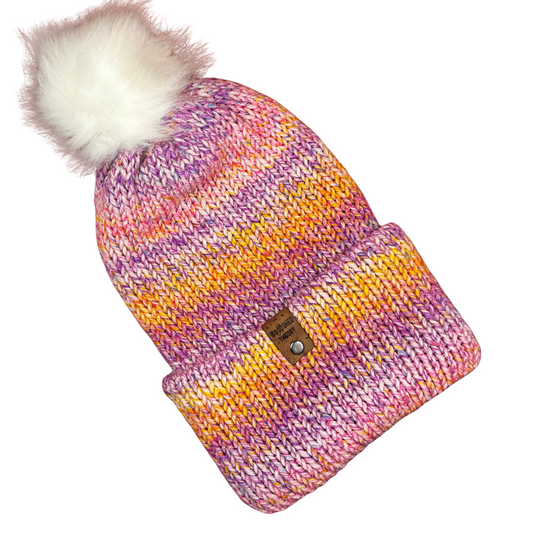 Pink, yellow, and orange acrylic knit beanie with removable faux fur pom and cork tag, hand crafted by Woodshed Theory fairy party front