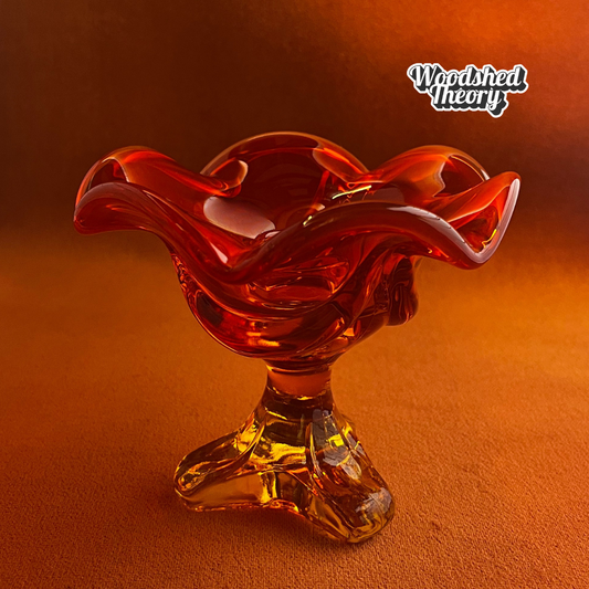 Viking Glass persimmon orange petal-shaped cadmium glass candle holder glowing under black light front