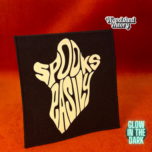 A glow-in-the-dark ghost-shaped iron-on patch that reads "Spooks Easily" in playful block lettering. The patch is handmade and approx. 5 by 5.5 inches. Front 