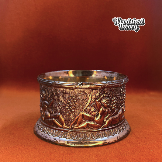 Fine English silver plate wine bottle coaster with cherub and grape design on a wood base. front cherub