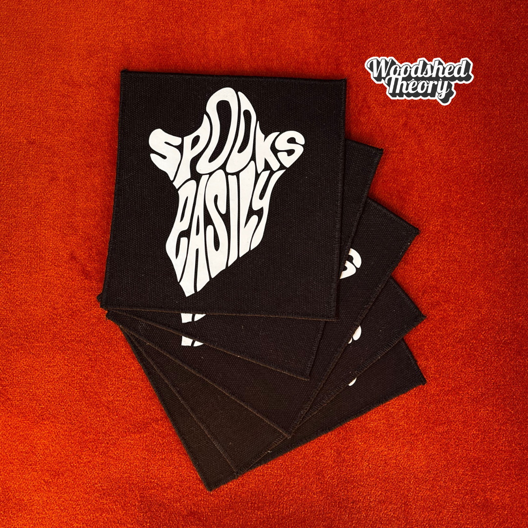 A glow-in-the-dark ghost-shaped iron-on patch that reads "Spooks Easily" in playful block lettering. The patch is handmade and approx. 5 by 5.5 inches. a group of woodshed theory patches