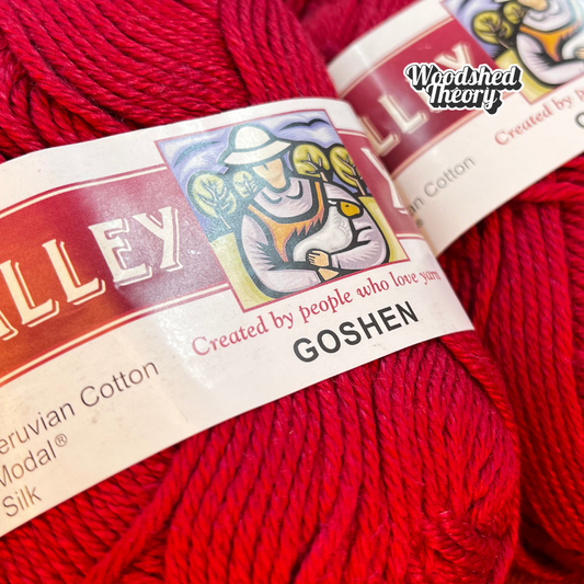 Five balls of Valley Yarns Goshen in vibrant red (color 06), cotton/modal/silk blend yarn, stacked neatly in a bundle. close up of label and color
