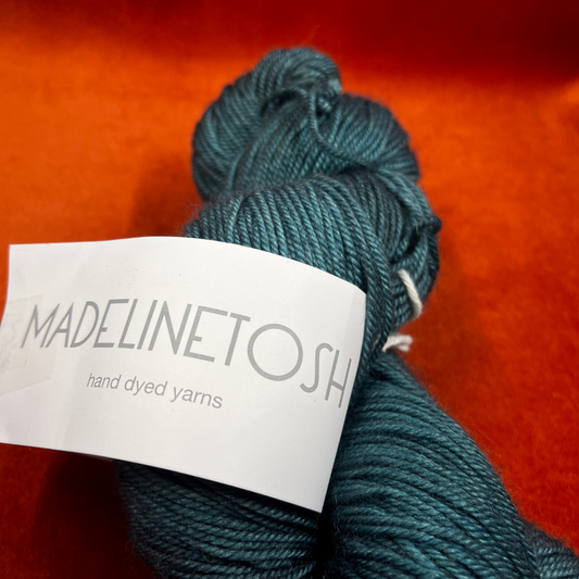 One skein of Madeline Tosh Pashmina yarn in Norway Spruce – a hand-dyed sport weight blend of merino, silk, and cashmere in deep green tones. close up label