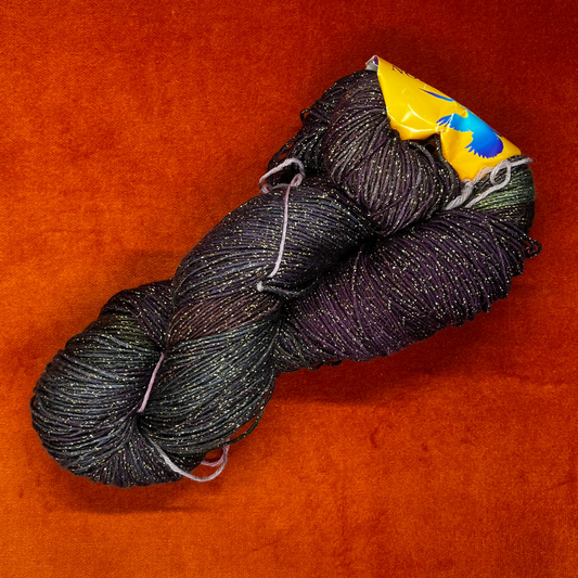 One hank of Blue Heron Rayon Gold Metallic yarn in a blend of purples, greens, and blues with gold shimmer. top down