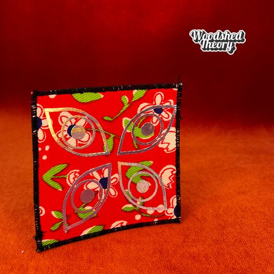 Square iron-on patch with four holographic eyes arranged like a butterfly on red vintage floral canvas. Approx. 4 x 4 inches. sensory issues autism patch