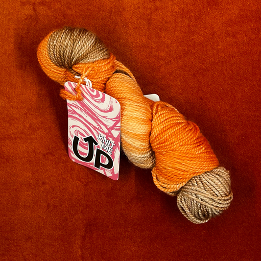 A skein of KnitMeUp 100% Merino Wool yarn in the hand-painted color "Tim," featuring warm orange and brown tones. Displayed partially unwound on a neutral background. top