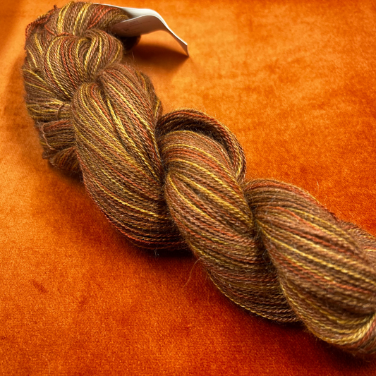 One hank of Knit Picks Shimmer lace weight yarn in a warm Spice color, made of baby alpaca and silk. close up 