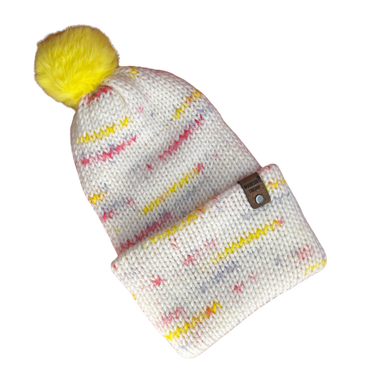 Knitted beanie with colorful pattern and yellow pom-pom on a white background the basic beanie in spring sprinkle