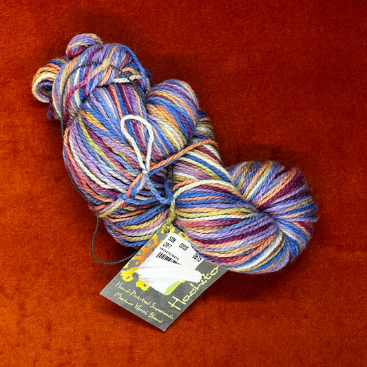 One hank of Mirasol Hachito fingering weight yarn in Maya, a superwash merino and nylon blend in rich, variegated tones. 