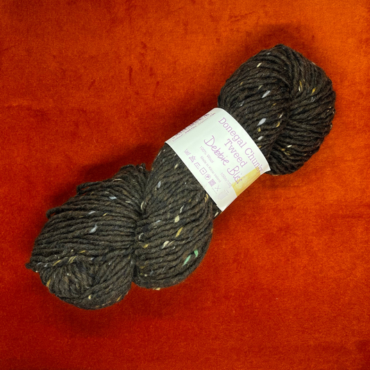 A hank of Debbie Bliss Donegal Chunky Tweed yarn in dark brown with multicolored flecks, 100% wool. top down