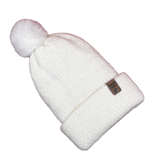 White knit beanie with a pom-pom on a white background alpaca snow beanie in snow hare bright white with custom tag and removable pom pom front flat 