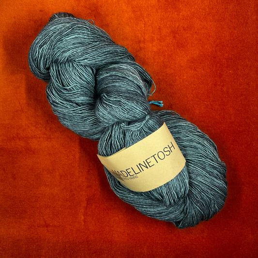 One skein of Madelinetosh Prairie yarn in Fog – a lace weight, single-ply merino wool yarn in deep teal tones. top down
