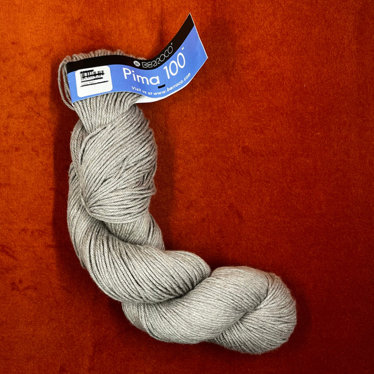 One hank of Berroco Pima 100 yarn in color Rye (8408), worsted weight matte beige cotton yarn. front down
