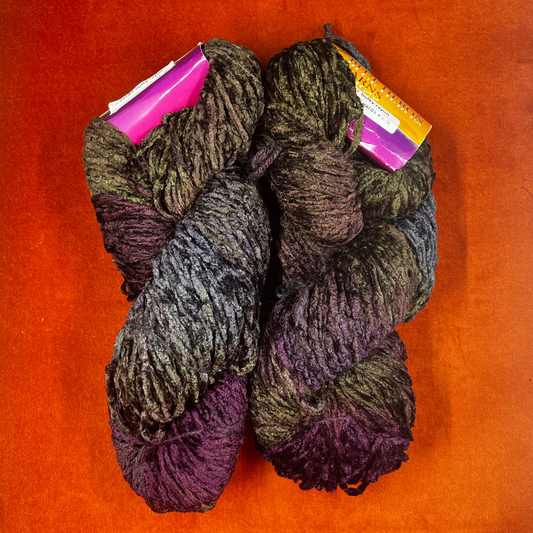 Two hanks of Blue Heron bulky rayon chenille yarn in a variegated blend of purples and greens with a plush, velvety texture. top down