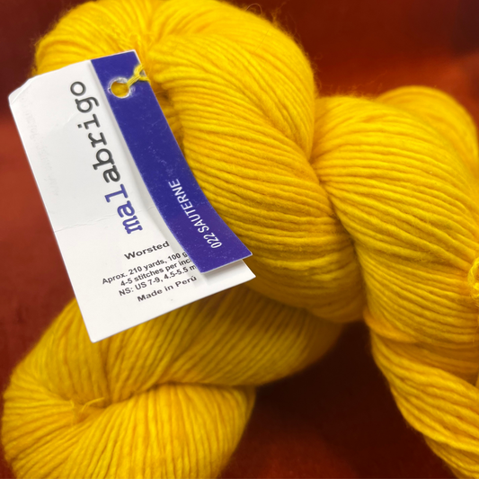 Two hanks of Malabrigo Worsted Roving in 022 Sauterne, a golden yellow 100% merino wool yarn, soft single-ply texture. close up