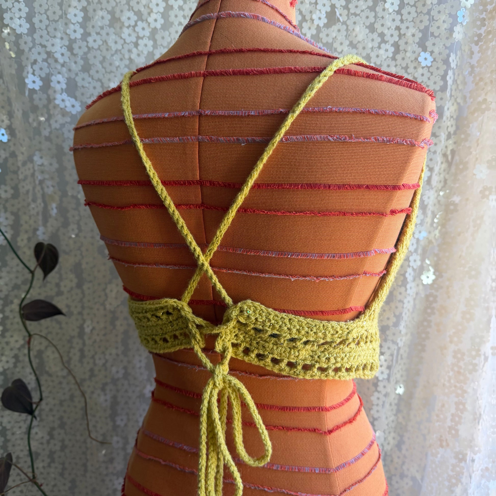 Mannequin wearing a striped dress with a yellow crochet top against a floral curtain background