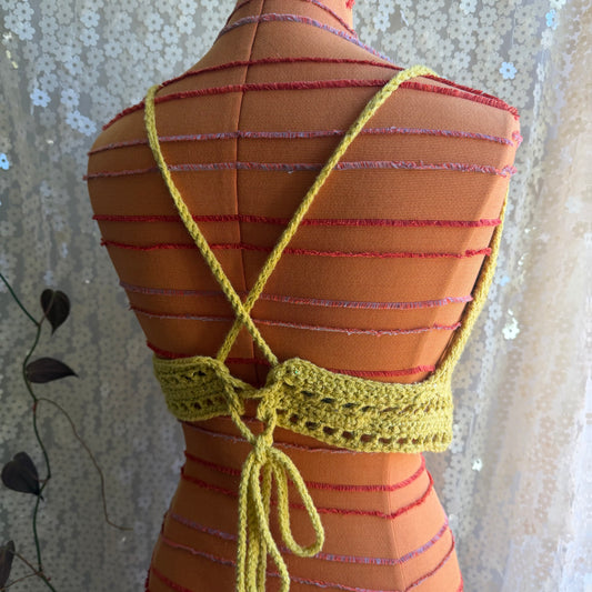 Mannequin wearing a striped dress with a yellow crochet top against a floral curtain background